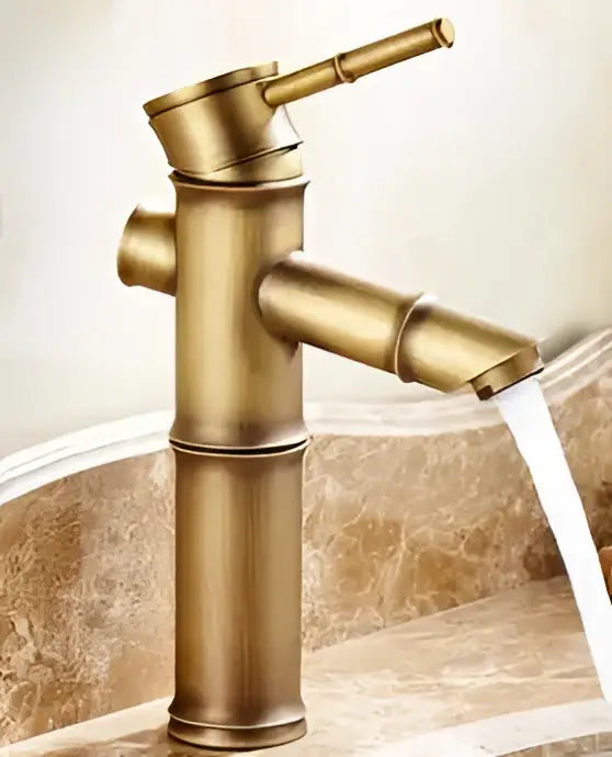 Brass bamboo-style decorbites antique brass single handle basin faucet with sleek segmented design and flowing water stream