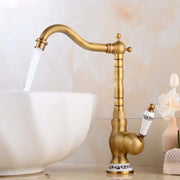 Decorbites antique brass basin faucet with curved spout and white ceramic handles featuring black floral patterns