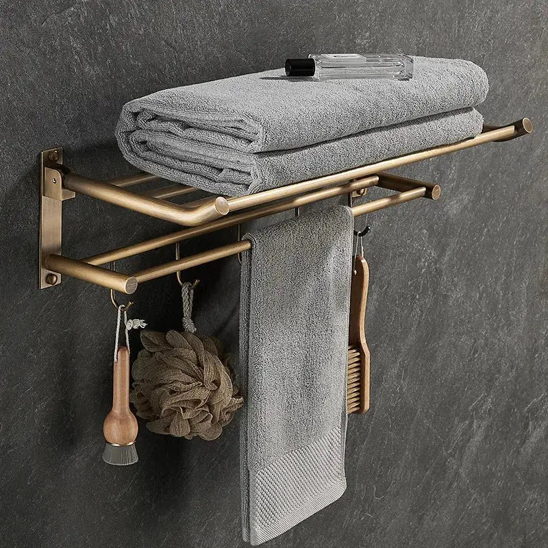 Brass bathroom accessory set featuring an antique brass double-tier towel rack with gray towels and hanging bath accessories