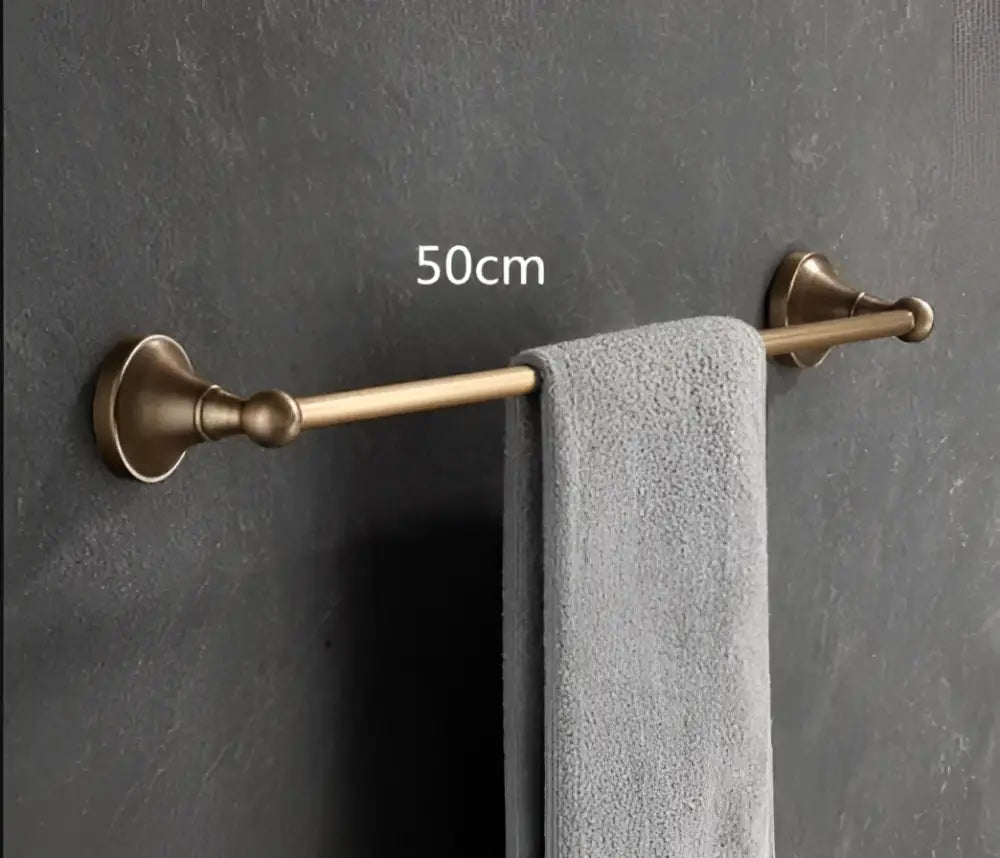 A 50cm bronze-finished towel rack with ornate vintage-style mounts holding a gray towel from the decorbites antique brass bathroom accessory set