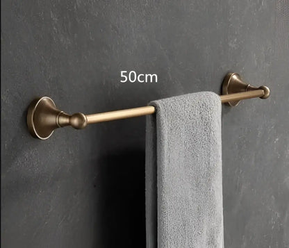A 50cm bronze-finished towel rack with ornate vintage-style mounts holding a gray towel from the decorbites antique brass bathroom accessory set