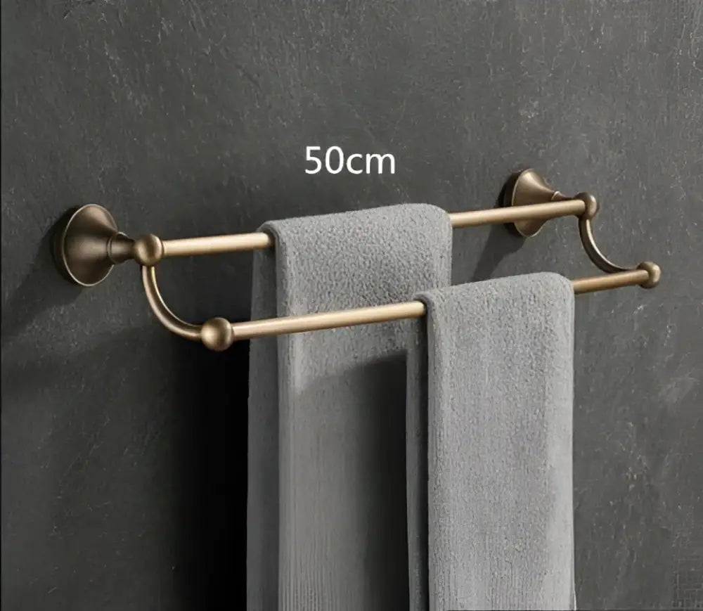 Antique brass bathroom double towel rack with elegant curved ends and two gray towels from decorbites bathroom accessory set