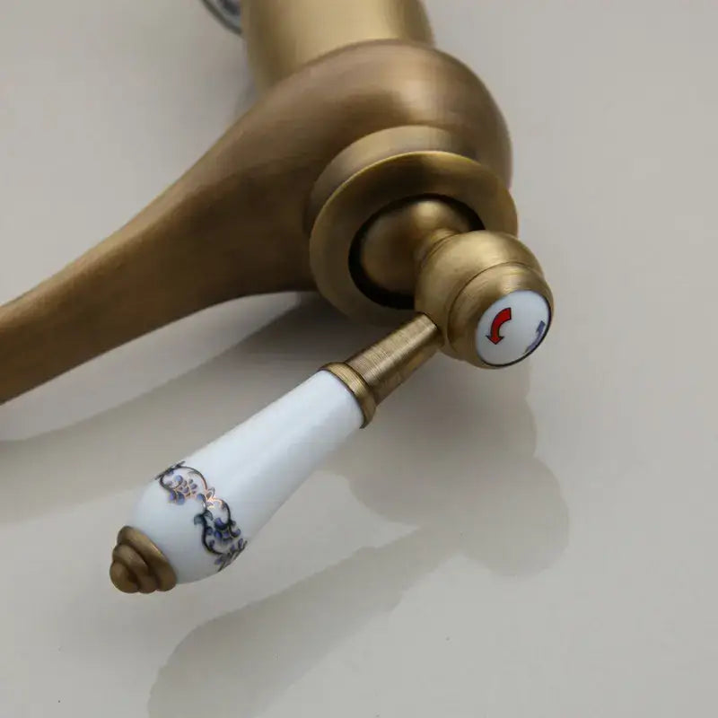 DecorBites antique brass bathroom basin faucet with white ceramic handle blue floral pattern and red arrow indicator
