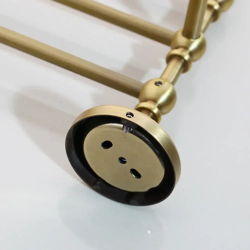 Brass-finished double towel rack with ornate spherical joints and circular mounting plate in antique brass bathroom hardware set