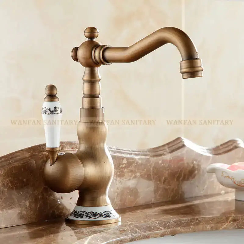 Antique brass bathroom sink faucet with white ceramic handle and base featuring black floral patterns by DecorBites