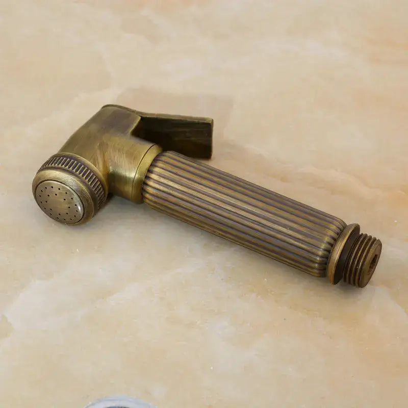 Decorbites™ antique brass bidet faucet wall mount with handheld shower sprayer featuring a ribbed handle and perforated nozzle