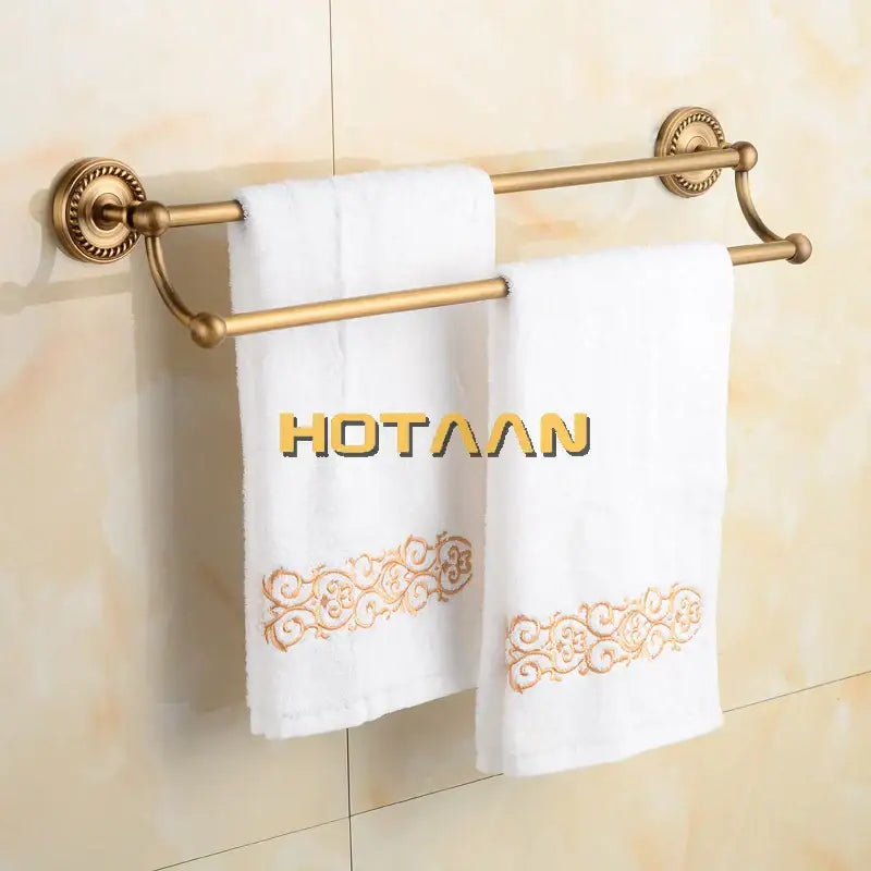 Decorbites antique brass towel bar rack with gold-finished double bars and ornate mounts holding embroidered towels