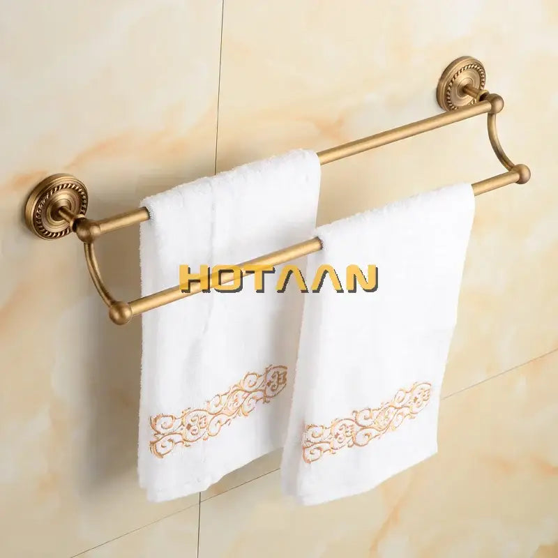 DecorBites™ antique brass double towel bar rack with ornate circular mounts holding two white towels with gold embroidery