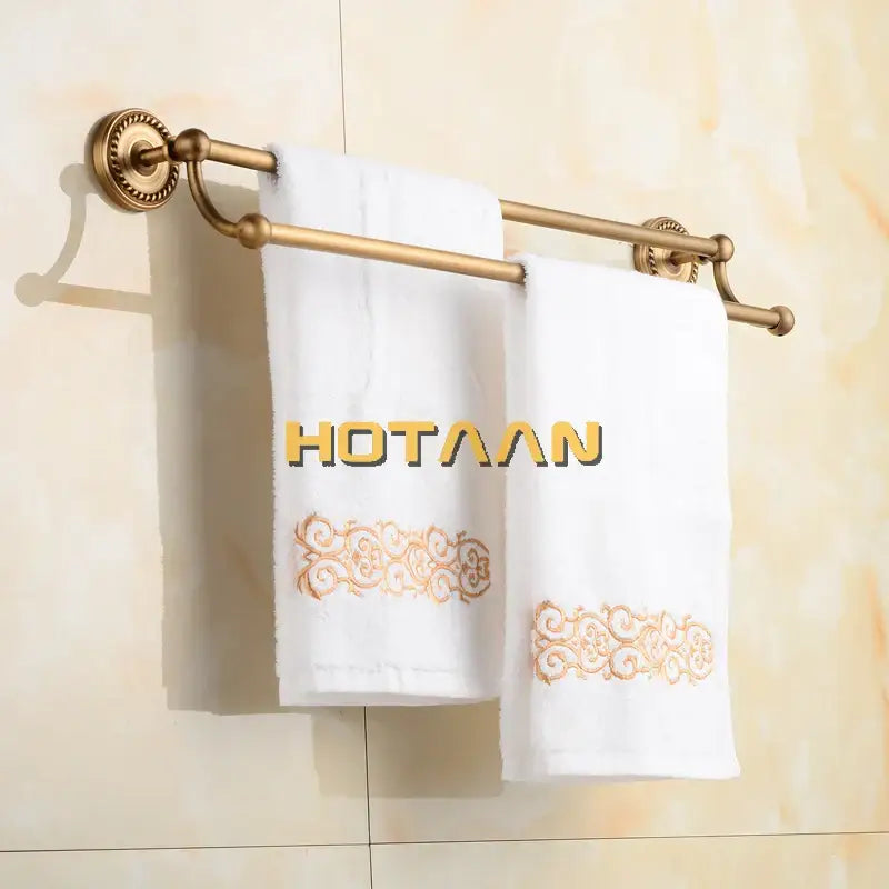White towels with gold embroidery hanging on a DecorBites™ antique brass double towel bar rack made of solid brass