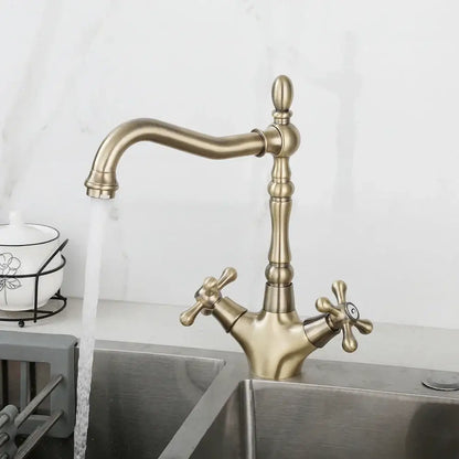 Antique brass dual handle DecorBites swivel sink faucet with ornate cross handles and curved spout in farmhouse style
