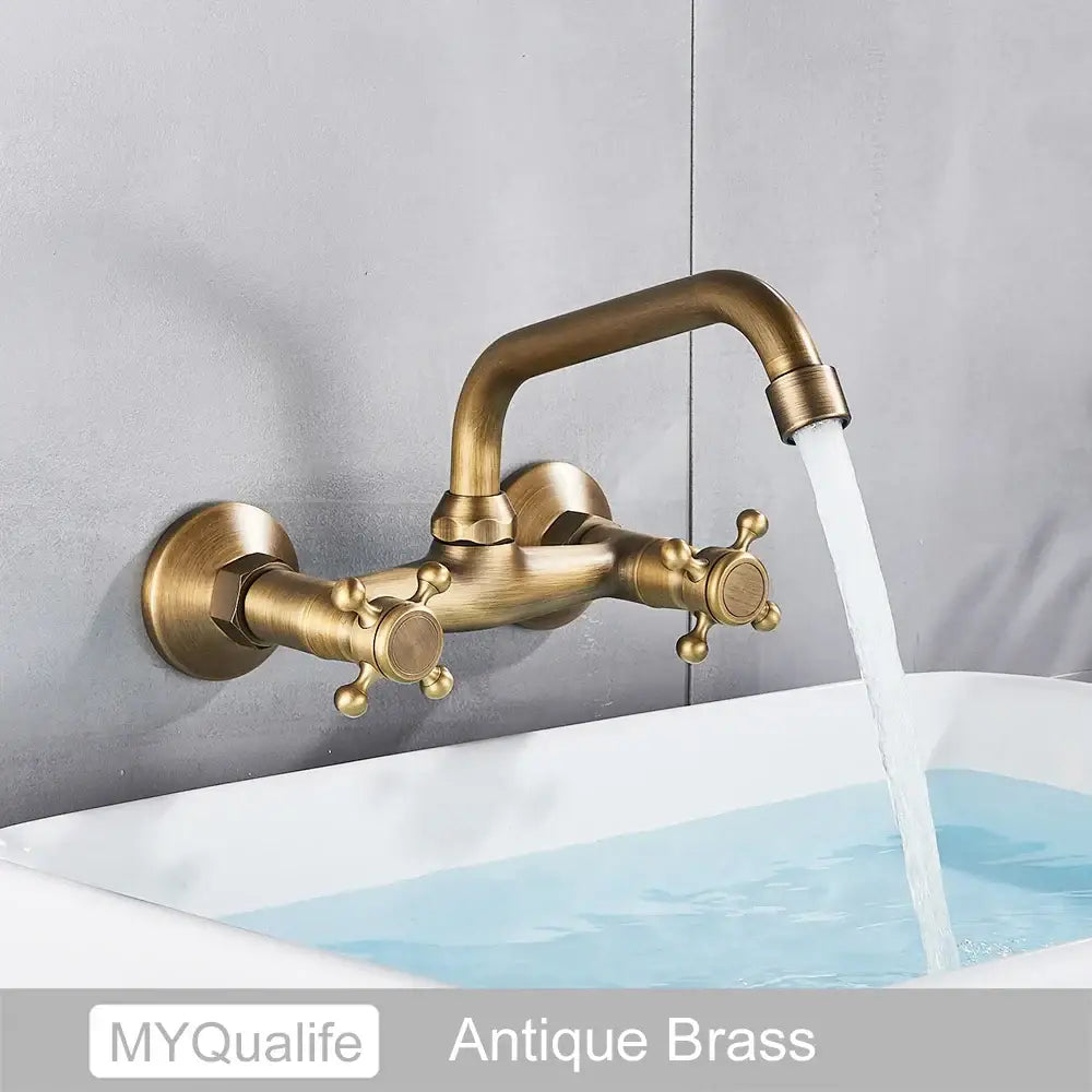 Antique brass dual handle kitchen faucet by decorbites with ornate cross knobs and curved spout wall mount design