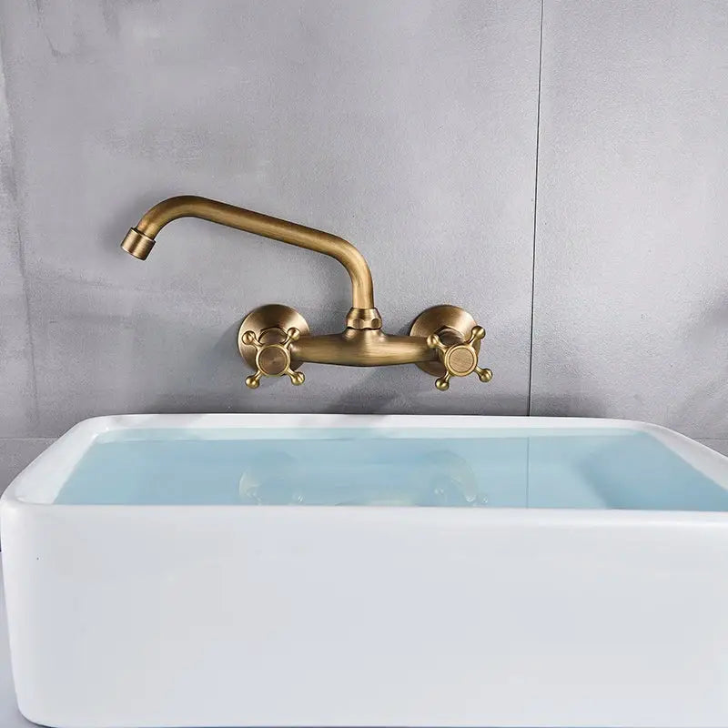 DecorBites™ antique brass dual handle wall mount kitchen faucet with two cross-handle knobs above white sink
