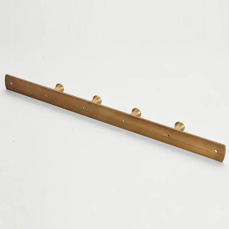 A sleek minimalist brass robe hook with antique brass finish and smooth wooden base featuring five circular hooks