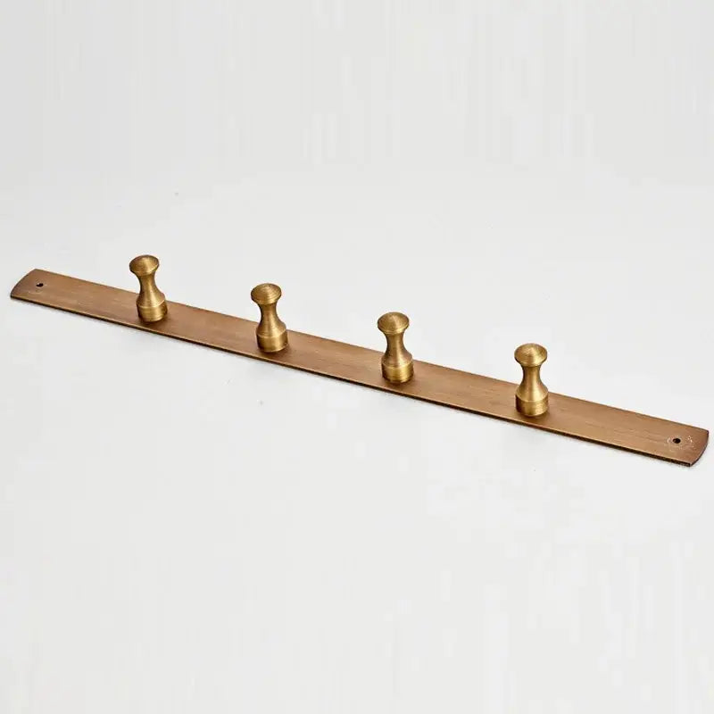 A sleek matte brass wall-mounted robe hook with antique brass finish and four rounded pegs for bathroom use