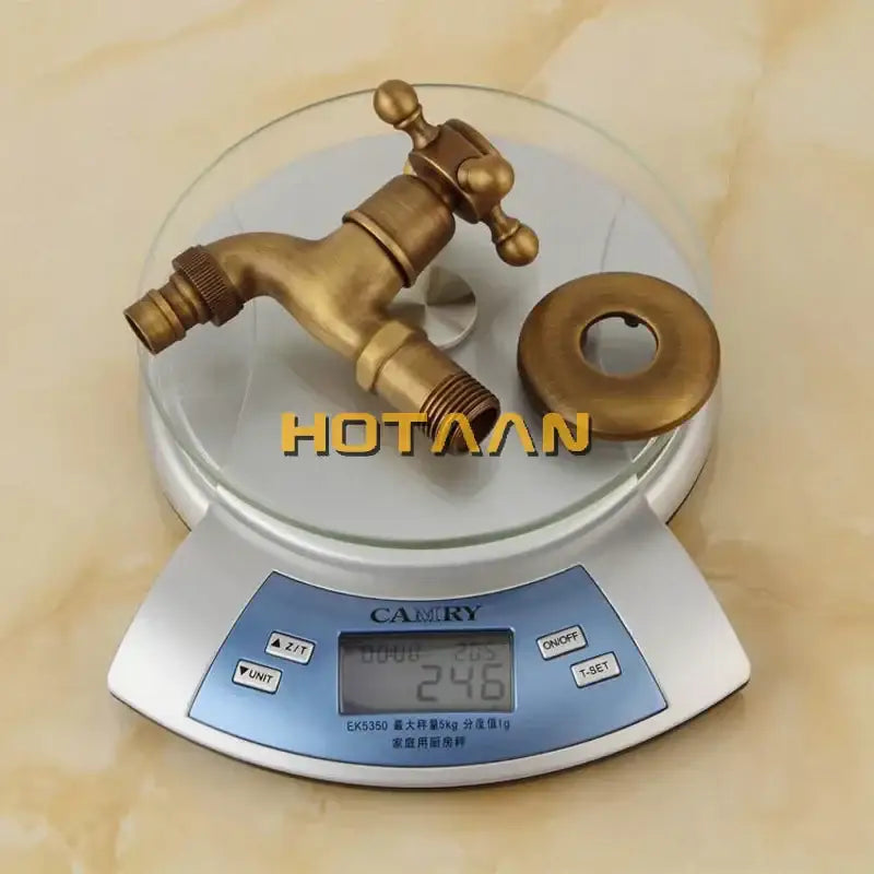 Decorbites™ antique brass finish wall mount garden bibcock faucet with matching flange on digital scale in brass finish