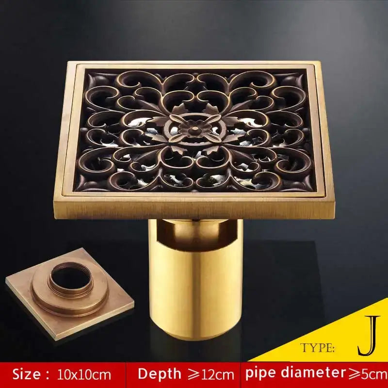 Square brass bathroom shower drain with ornate floral antique brass fish style cutout and matching cylindrical pipe