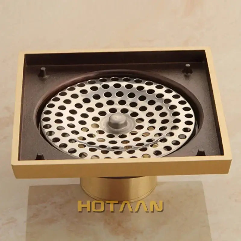 DecorBites antique brass floor drain with circular perforated grate and central knob featuring flower art design