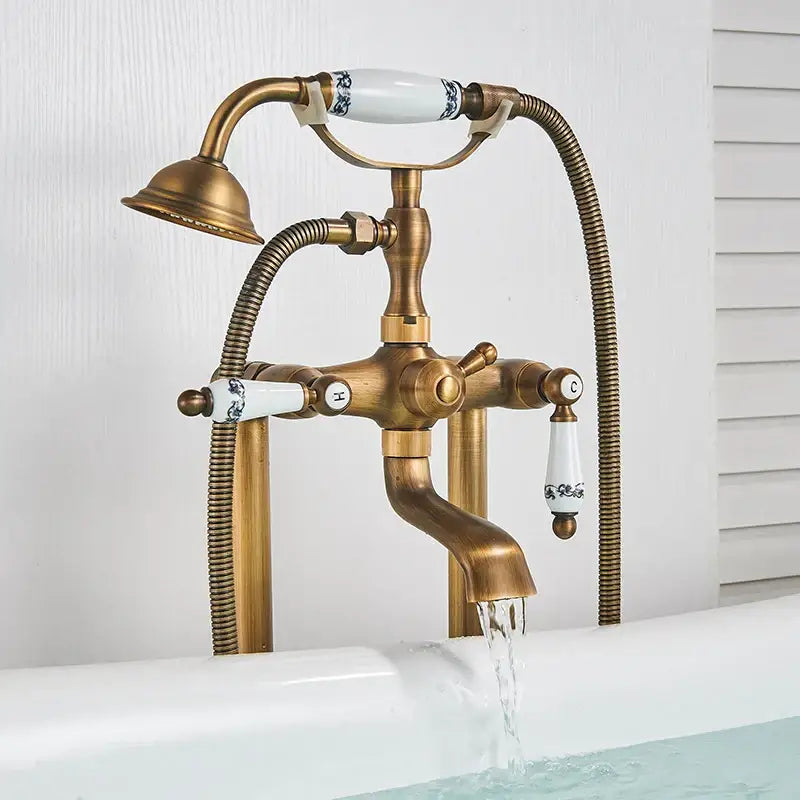 Decorbites antique brass freestanding bathtub filler with white ceramic handles and flexible hand shower in brass freestanding bathtub design