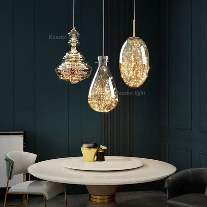 Three elegant antique brass glass pendant lights with warm fairy lights hang above a dining table in a brass glass chandelier