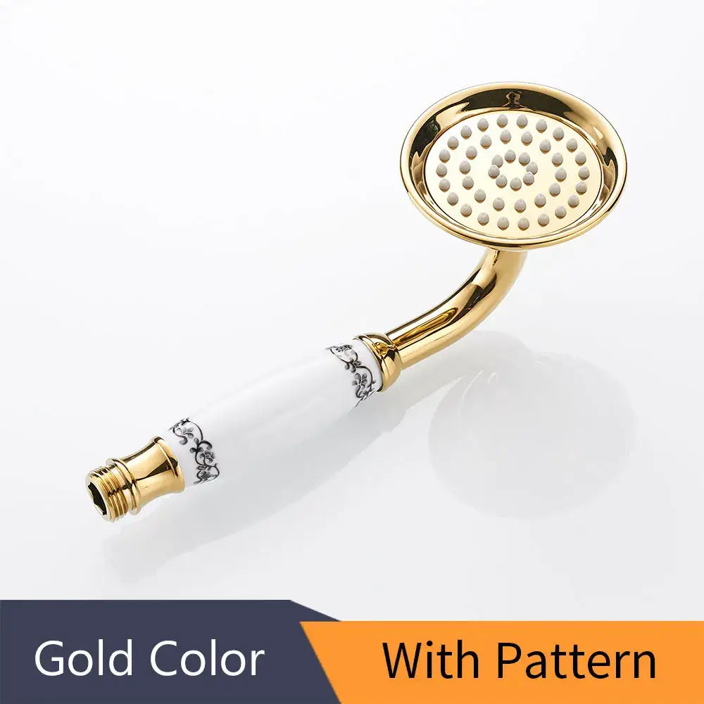 Gold-colored brass hand held shower with white ceramic handle featuring black floral patterns in antique brass hand style