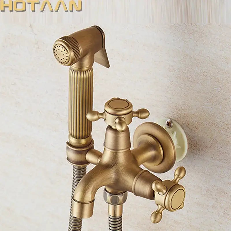 Antique brass handheld bidet sprayer set with wall-mounted faucet and two ornate cross-handle knobs by DecorBites