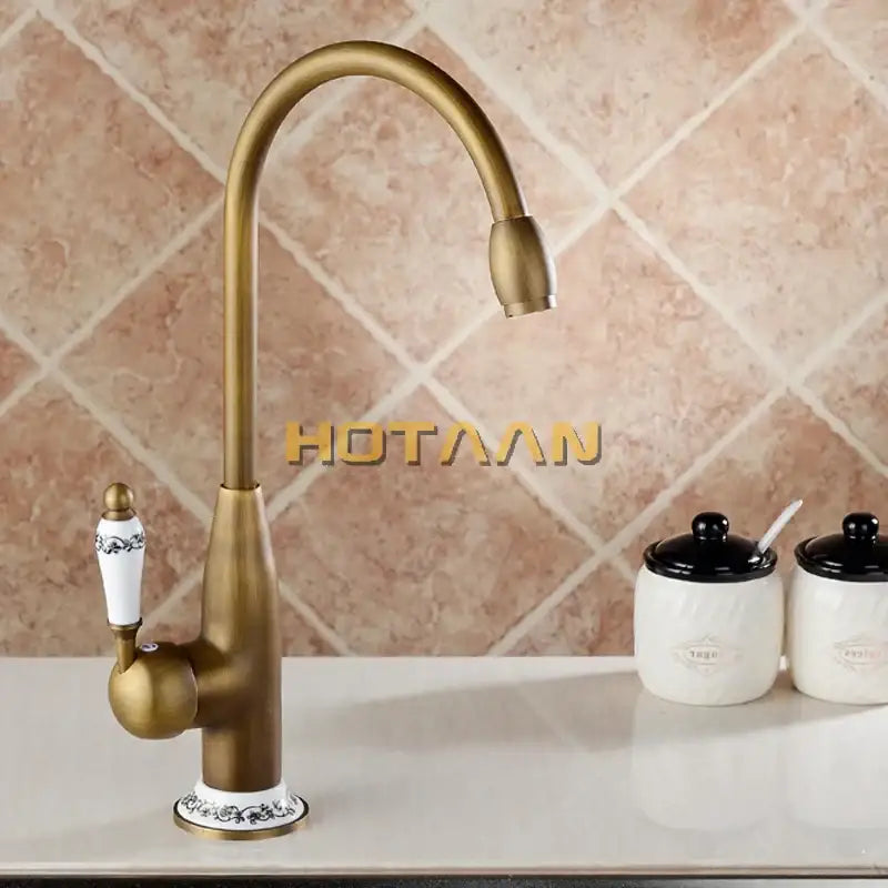DecorBites™ antique brass kitchen faucet with curved spout and white ceramic handle featuring black floral detailing