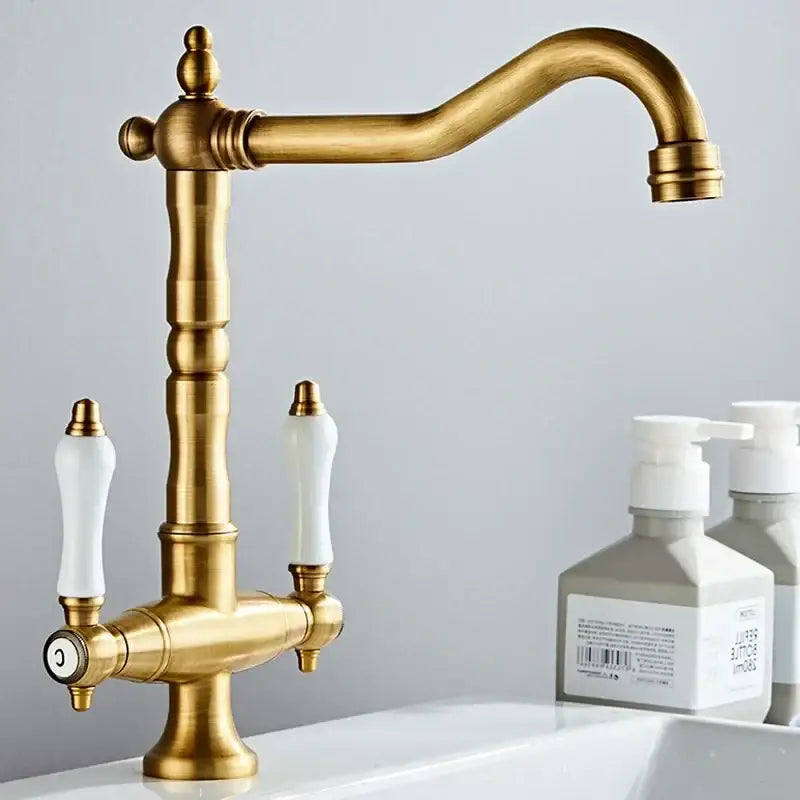 DecorBites antique brass kitchen faucet with dual white ceramic handles and a curved spout with 360 rotation