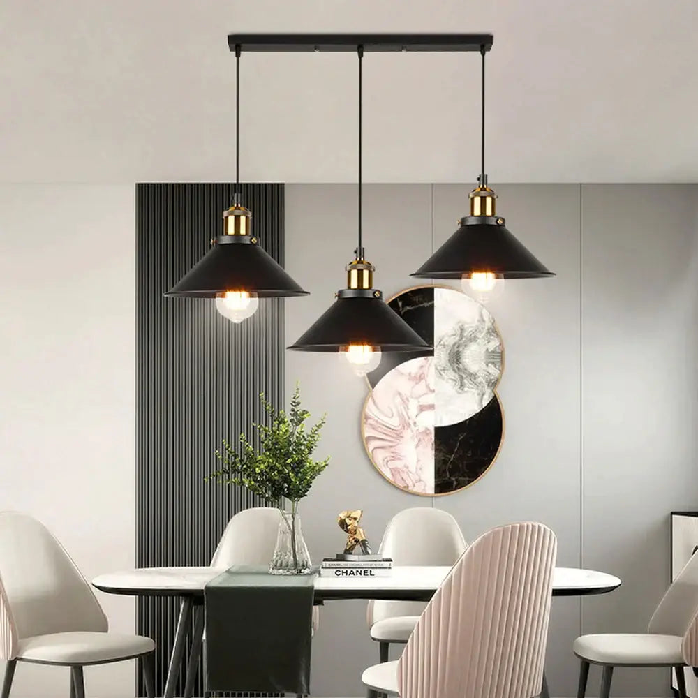 Black industrial-style pendant light with antique brass kitchen accents hanging above a dining table by DecorBites