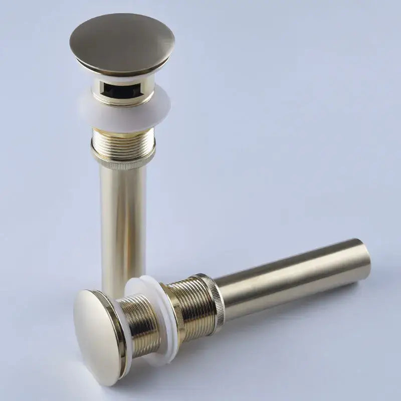 Two brushed brass antique brass bathroom sink drains with white ceramic washers and flat circular tops in drain kit