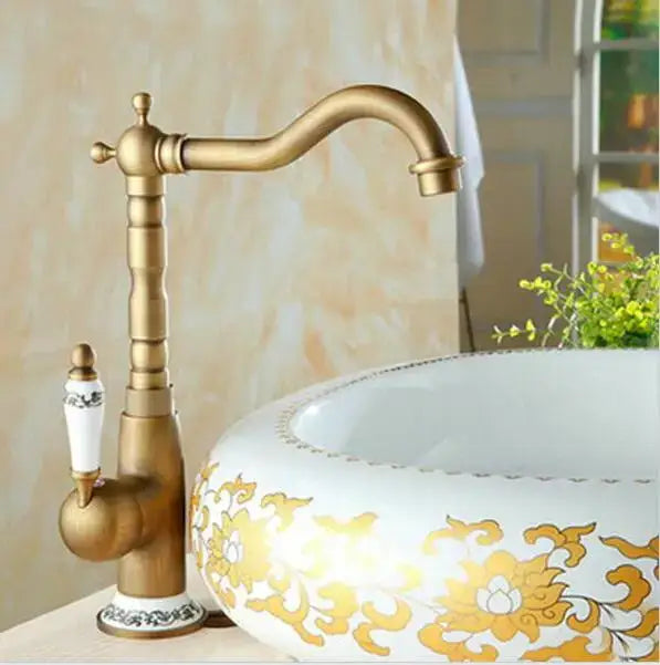 Antique brass porcelain basin mixer with ornate fluted spout and white ceramic handle with black floral detailing
