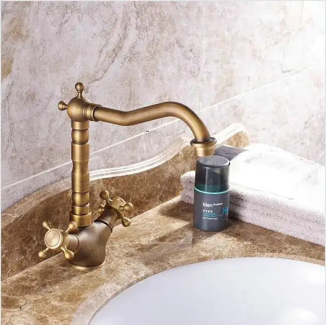 Antique brass porcelain basin mixer with ornate cross handles and curved spout for bathroom use by decorbites