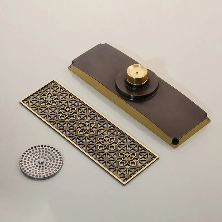 Decorbites antique brass floor drain strainer with intricate floral cutouts in brass and dark bronze finish