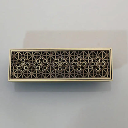 Bronze-colored antique brass floor drain strainer with intricate floral cutout and brushed finish for deodorization