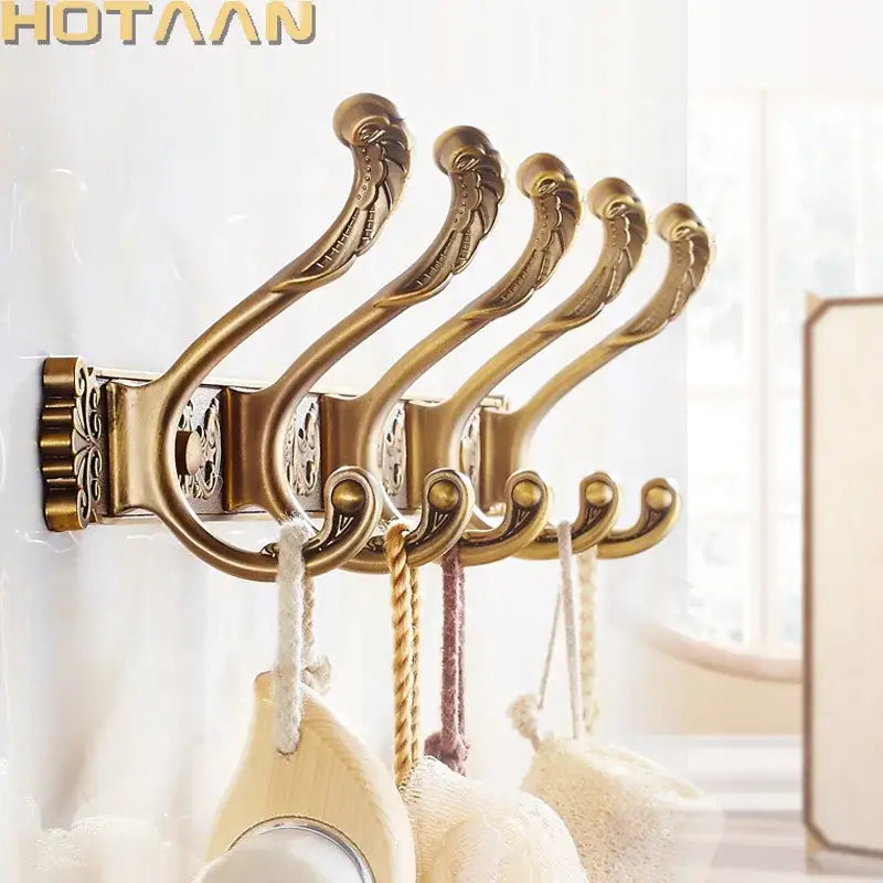 Antique brass robe hook wall mount with ornate curved designs and decorative cutouts for bathroom accessories