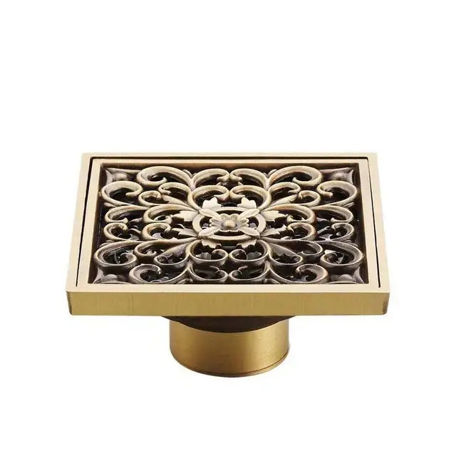 Rectangular antique brass shower floor drain with ornate scrollwork design for decorative bathroom waste strainer cover