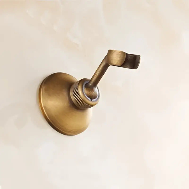 Antique brass wall-mounted towel rack with curved hook and circular base for DecorBites™ antique brass shower set