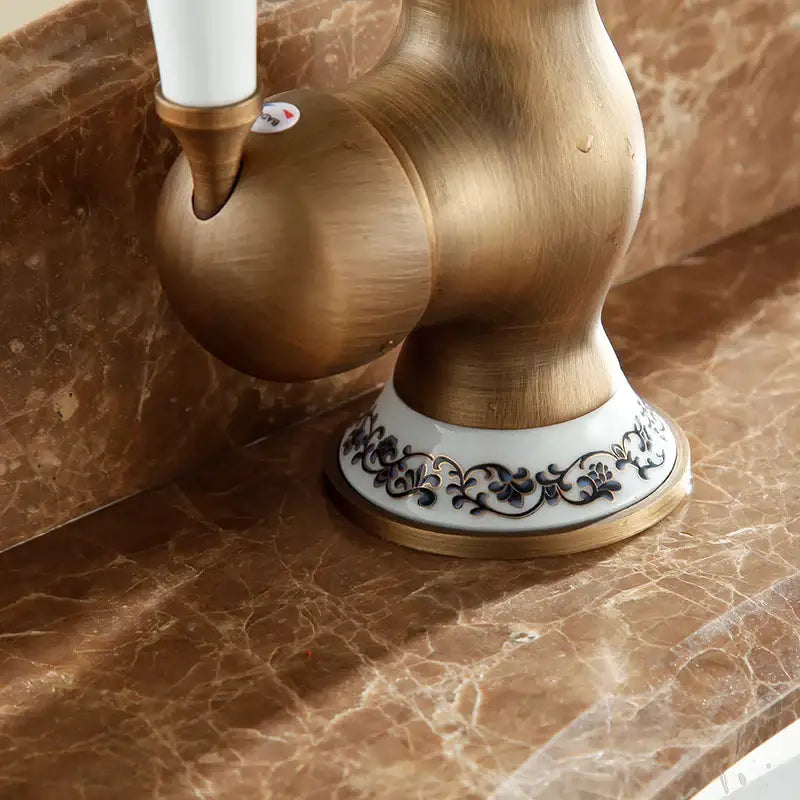 Decorbites antique brass single handle basin faucet with white ceramic base and black floral patterns swivel spout