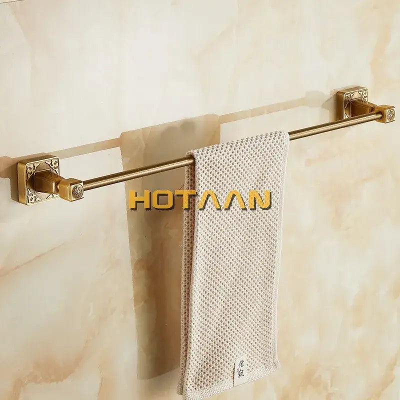 DecorBites™ antique brass single towel bar features gold-toned brass with ornate mounts and a textured beige towel