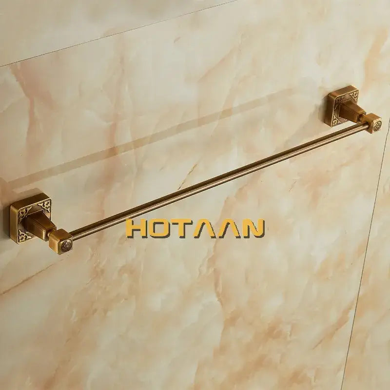 Decorbites antique brass single towel bar with brass finish and ornate square end caps mounted on marble wall