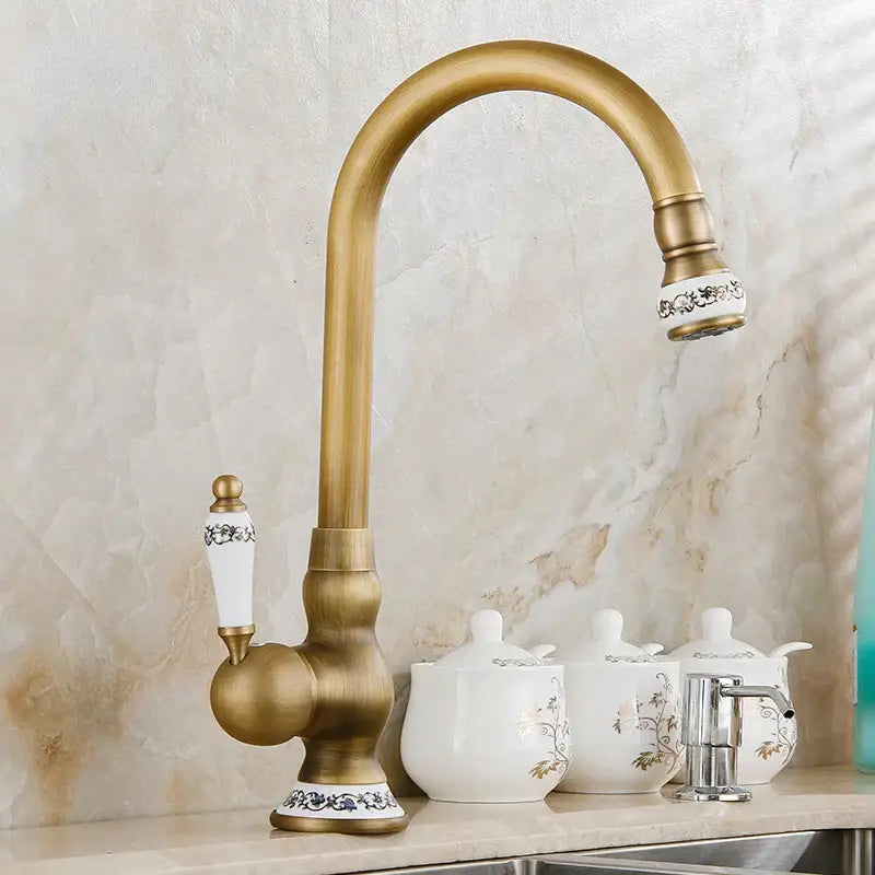 Decorbites™ antique brass swivel spout kitchen faucet with ornate white ceramic handles and decorative floral patterns