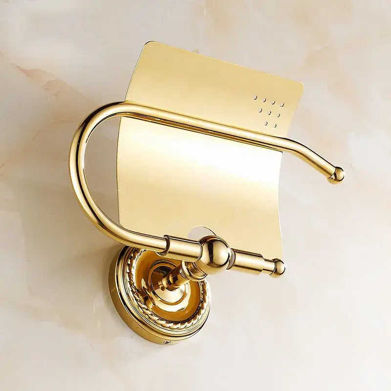 Gold-toned brass antique brass toilet paper holder with curved ornate design and fluted base for wall mount bathroom use