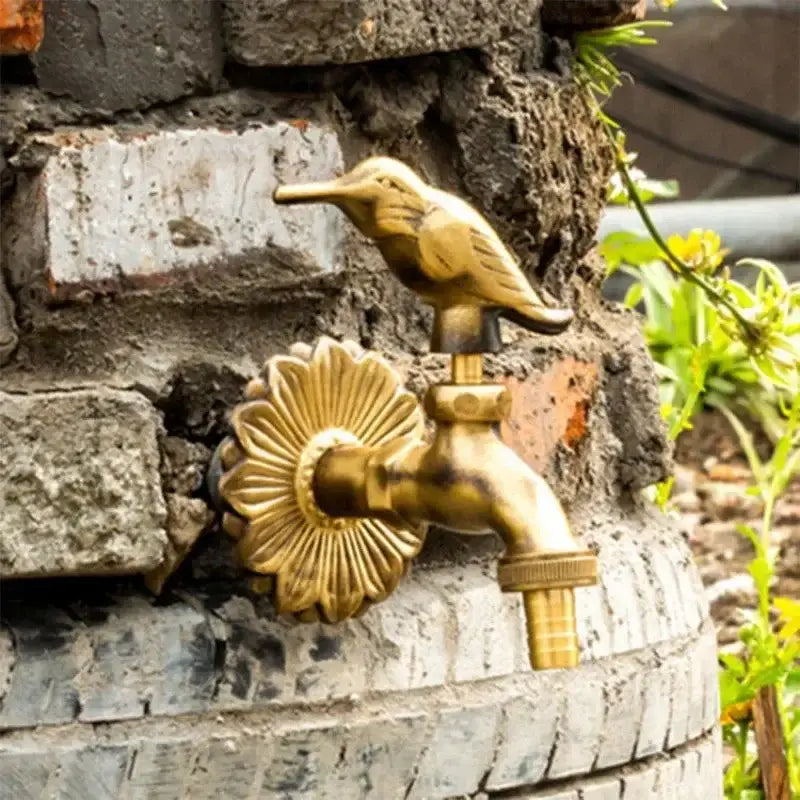 Decorbites antique brass wall mount garden faucet featuring a brass hummingbird spout and ornate sunburst design
