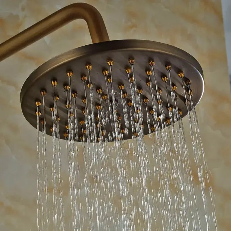 Antique brass wall mount shower faucet with 8 inch round rain shower head and multiple jets on curved arm