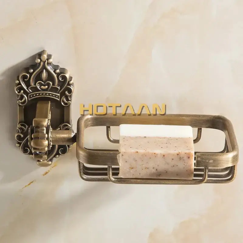Antique brass wall-mounted soap basket by decorbites with ornate crown design and wire mesh tray holding soap bar
