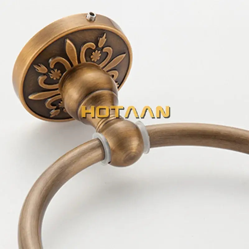 DecorBites antique brass round towel holder with ornate floral embossing on the mounting plate for bathroom use
