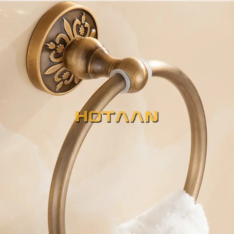 Decorbites antique brass round towel holder with ornate floral detail on mounting plate for classic bathroom use