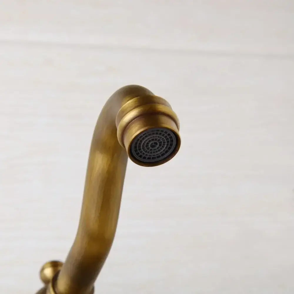 Antique brass wall mounted shower faucet by decorbites with a curved spout and circular spray head in antique brass finish
