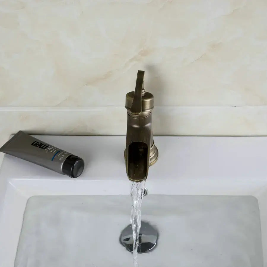 Decorbites™ antique brass waterfall basin faucet with art design handle featuring a sleek modern water stream