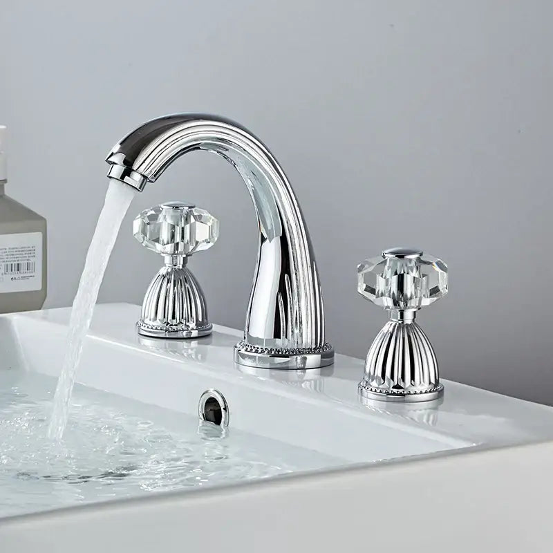Chrome-finished hole widespread basin faucet with three handles and crystal knobs mounted on white sink by decorbites