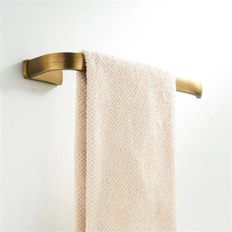 A cream-colored textured towel hangs on a sleek antique bronze bathroom accessory towel rack by decorbites